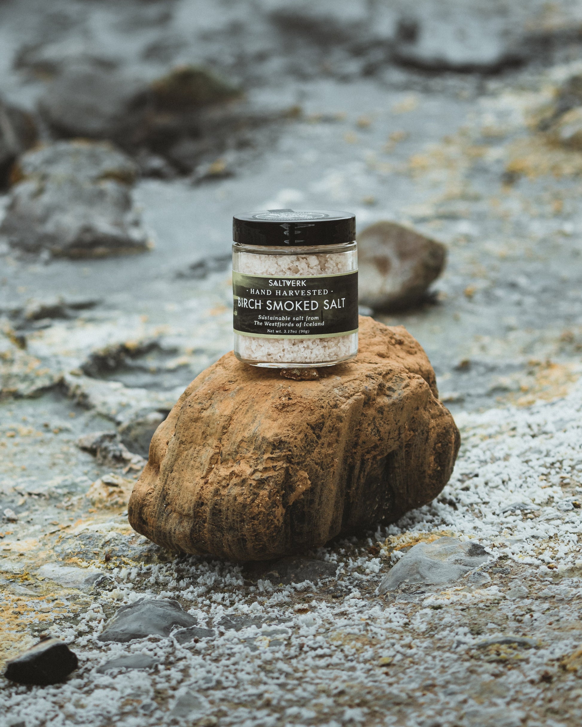 Jar of smoked salt on a rock with a rocky background